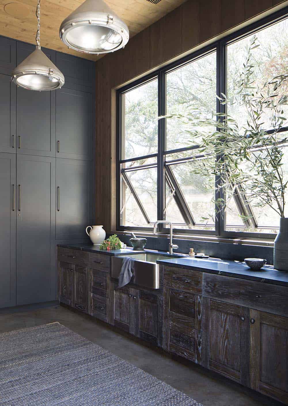 Dark kitchen with slate blue cabinetry, soapstone counters and industrial pendant lights