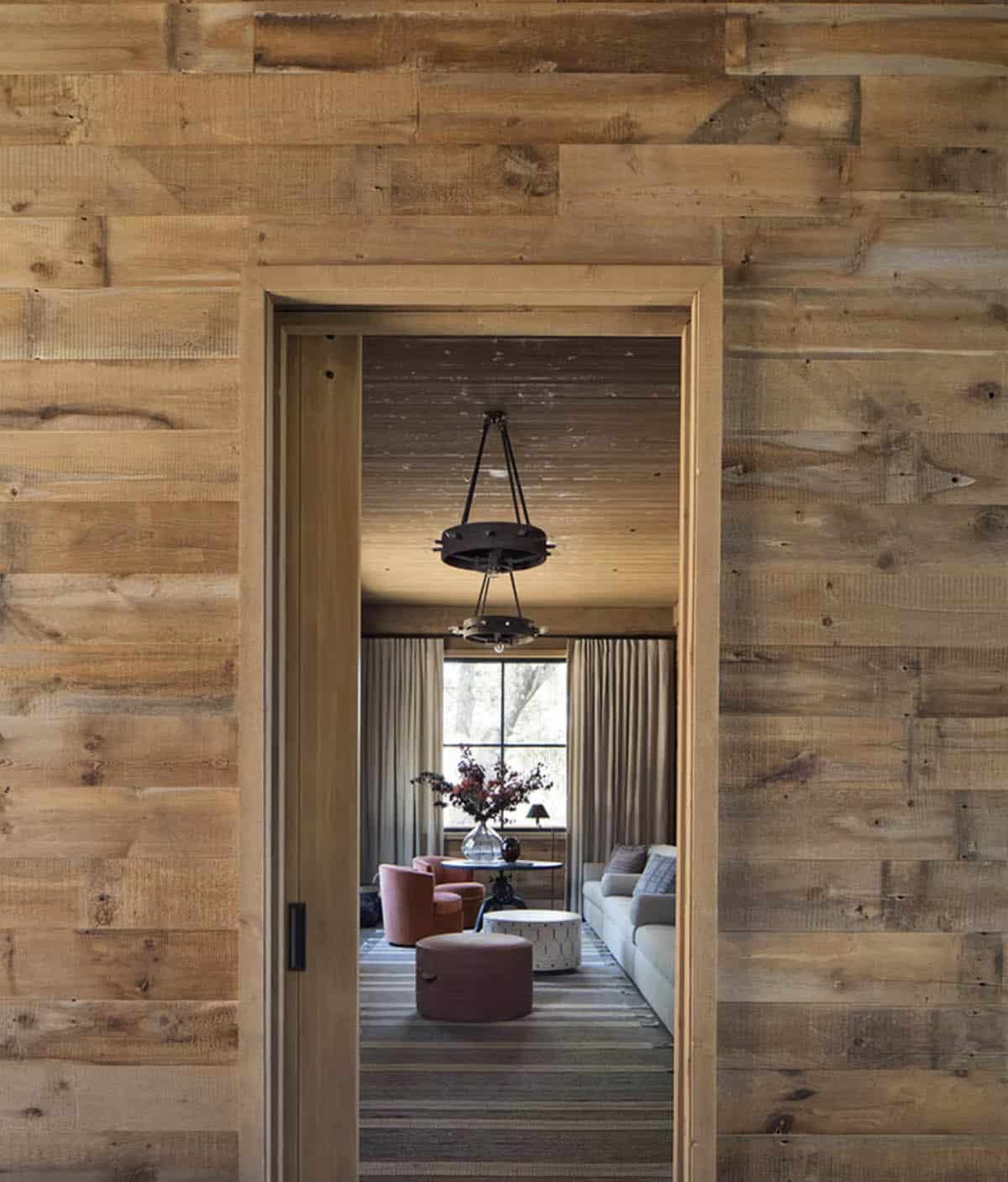 Reclaimed wood doorway framing view into cozy sitting room with rose velvet chairs