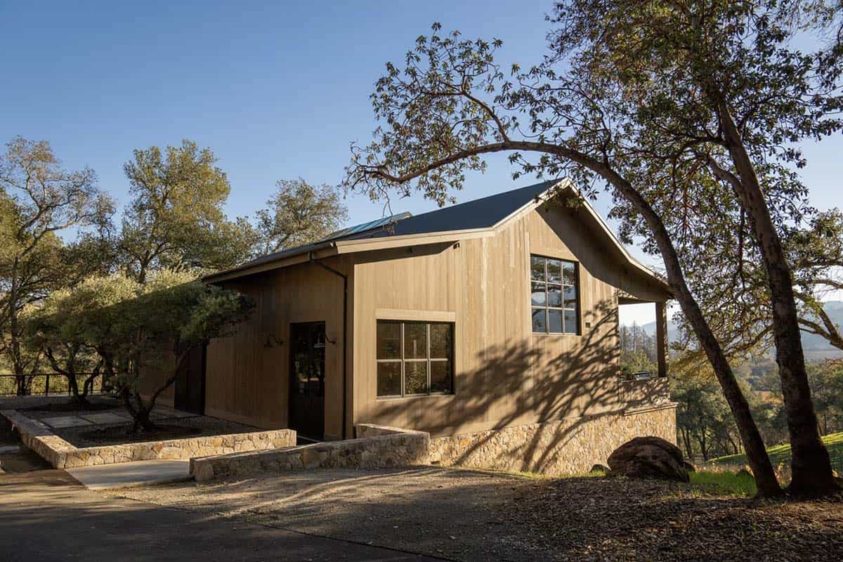 Party barn exterior with cedar siding, stone base and metal roof among Napa Valley oak trees