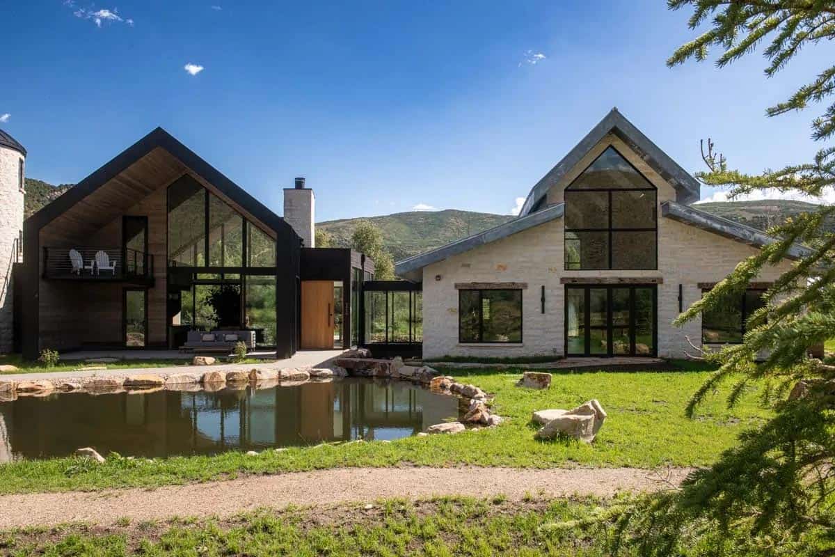 Twin gabled structures connected by glass bridge with Wasatch mountain backdrop, Utah ranch