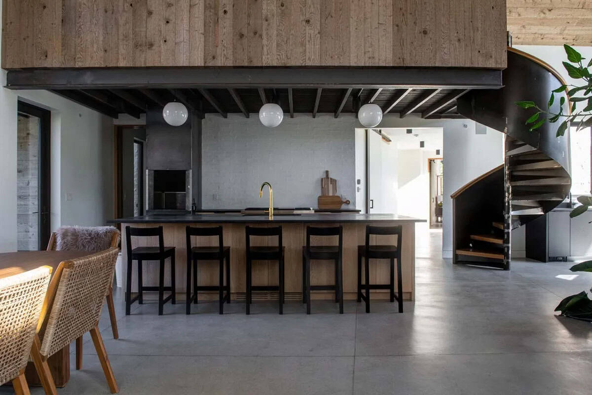 Open-plan kitchen with dark concrete island, brass faucet, globe pendants, and spiral staircase, Utah ranch