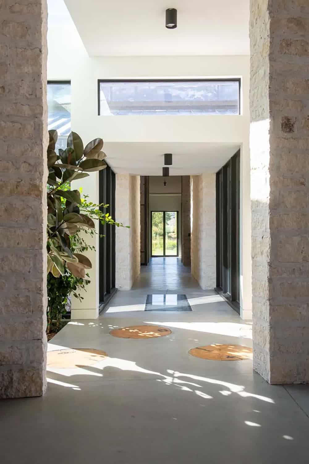 Stone-framed hallway with polished concrete floor, live-edge wood inlays, and natural light from clerestory windows