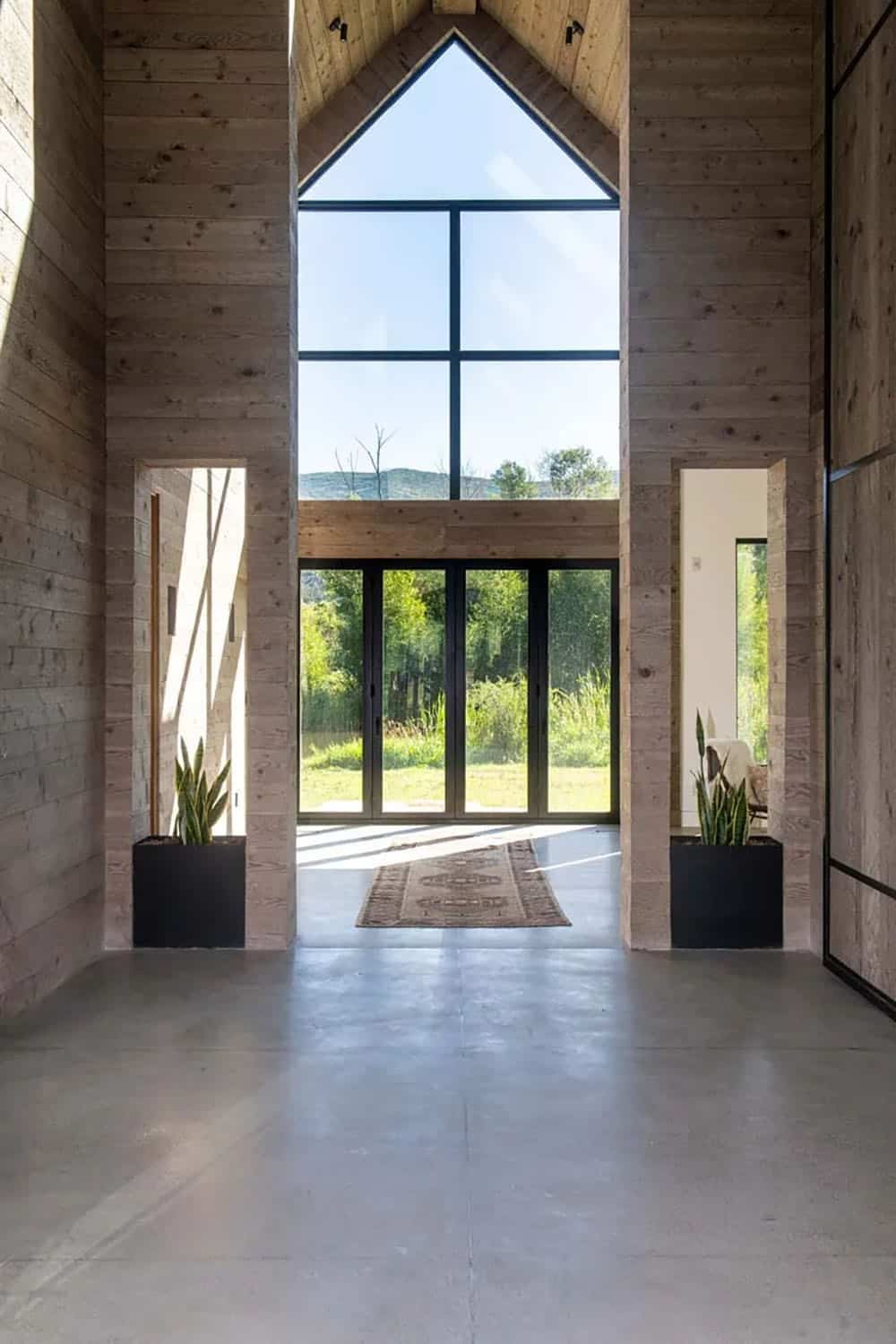Soaring barn-style interior with cathedral wood ceiling, concrete floor, and full-height glazed gable end