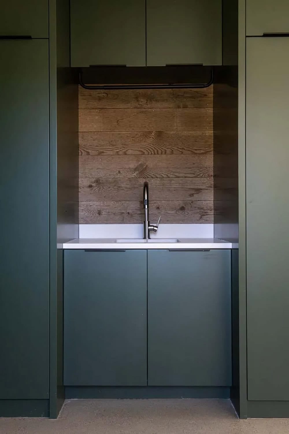 Matte olive green cabinetry with reclaimed wood backsplash and integrated sink, contemporary ranch kitchen detail