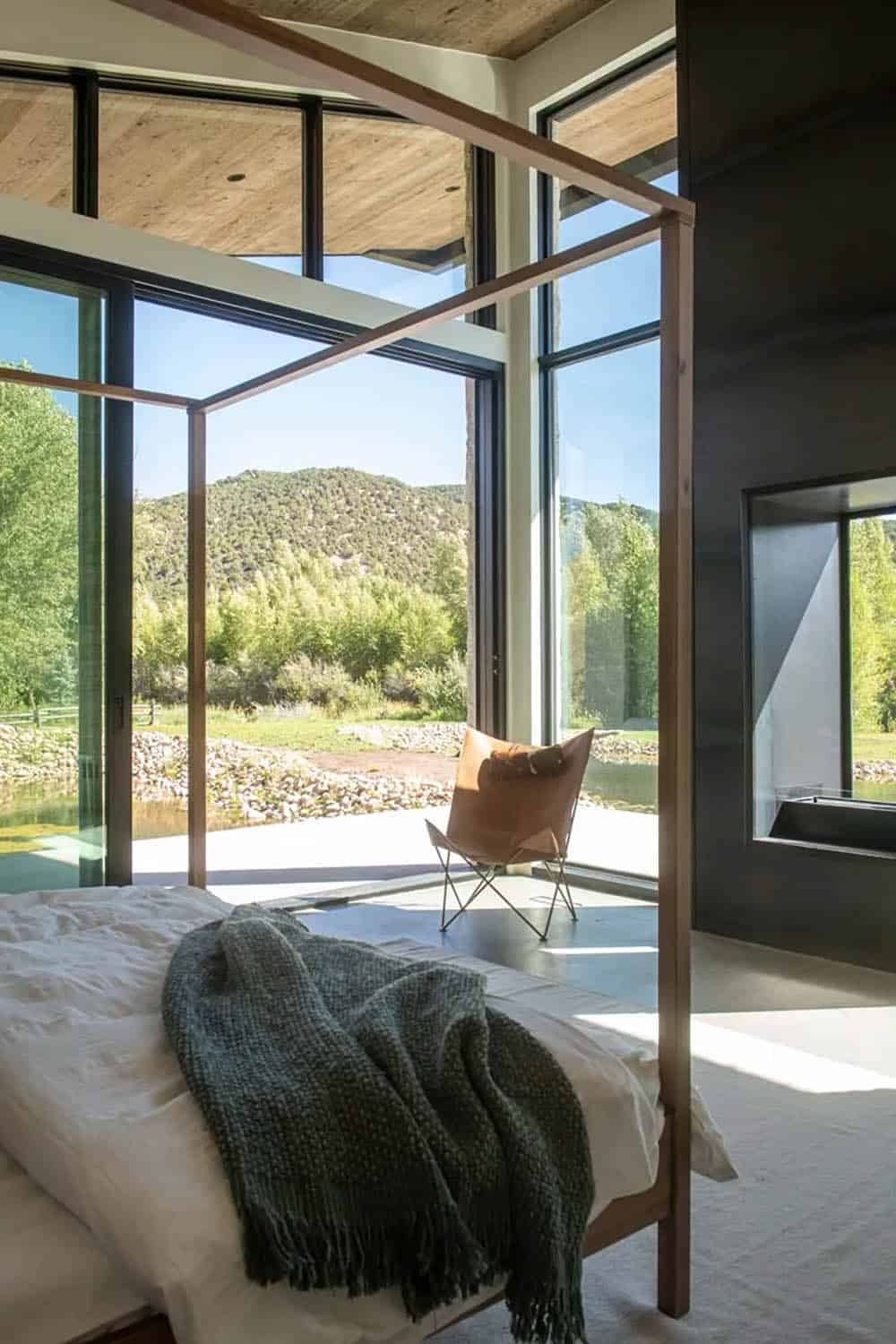 Four-poster canopy bed with mountain and pond views through corner floor-to-ceiling glazing, Utah ranch bedroom