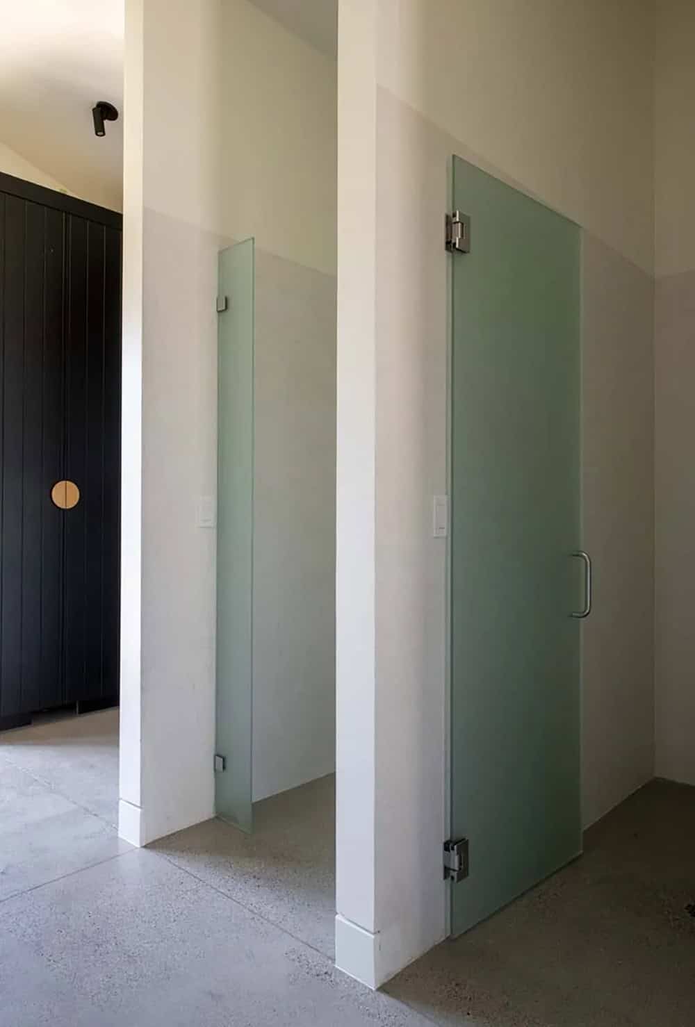 Frosted glass interior doors flanking a minimalist hallway with black vertical-board storage cabinet beyond