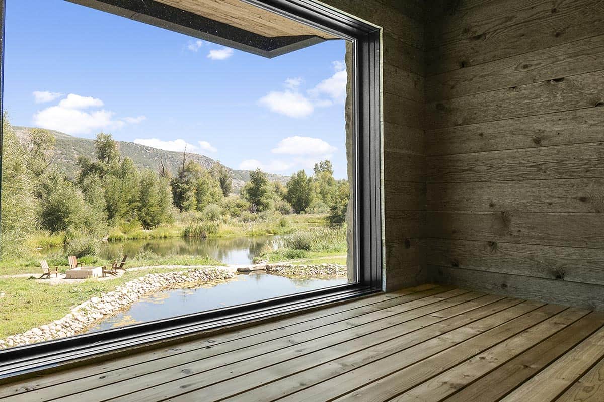 Sauna interior with large picture window overlooking a river pond and Adirondack chairs
