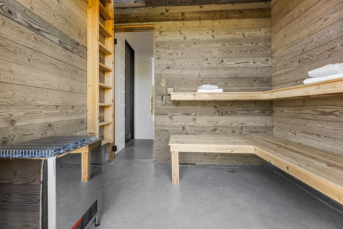 Steam room or cold plunge area with wood-lined walls, benches, and folded towels