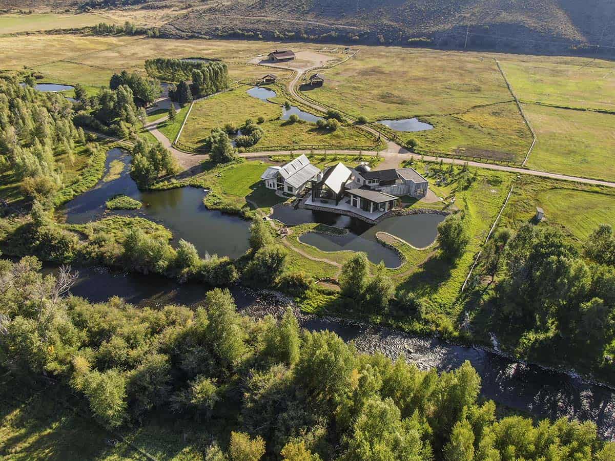Aerial view of riverfront ranch with multiple ponds, winding paths, and river access