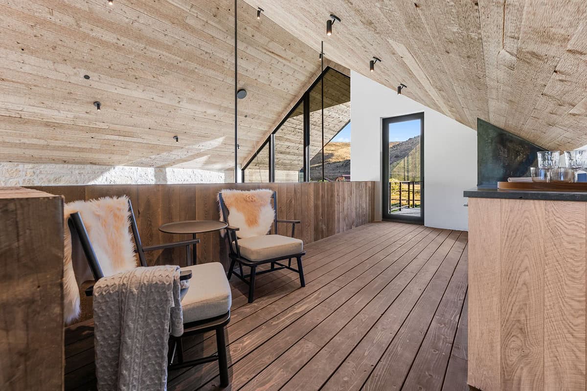 Modern kitchen with oak cabinetry, black stone countertops, globe pendants, and spiral staircase