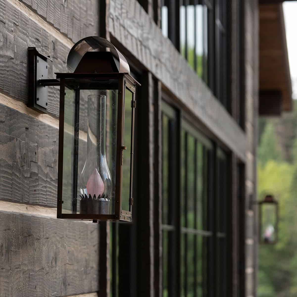 Vintage iron lantern sconce mounted on hand-hewn log exterior siding