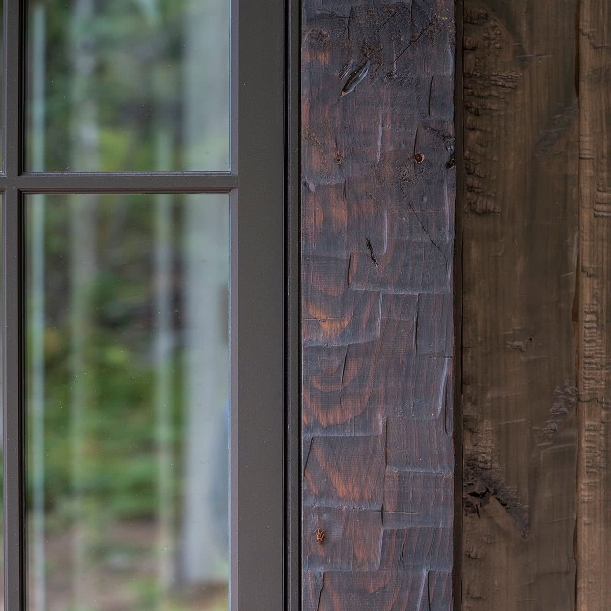 Close-up detail of hand-hewn fir timber and chinking beside a black-framed window