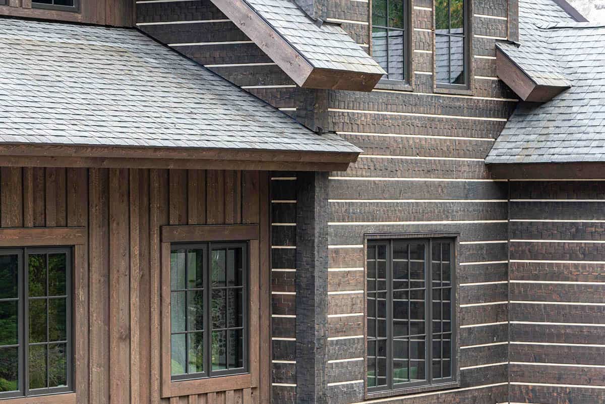 Exterior detail showing the juxtaposition of salvaged poplar bark shingles and clean vertical wood siding with black-framed windows
