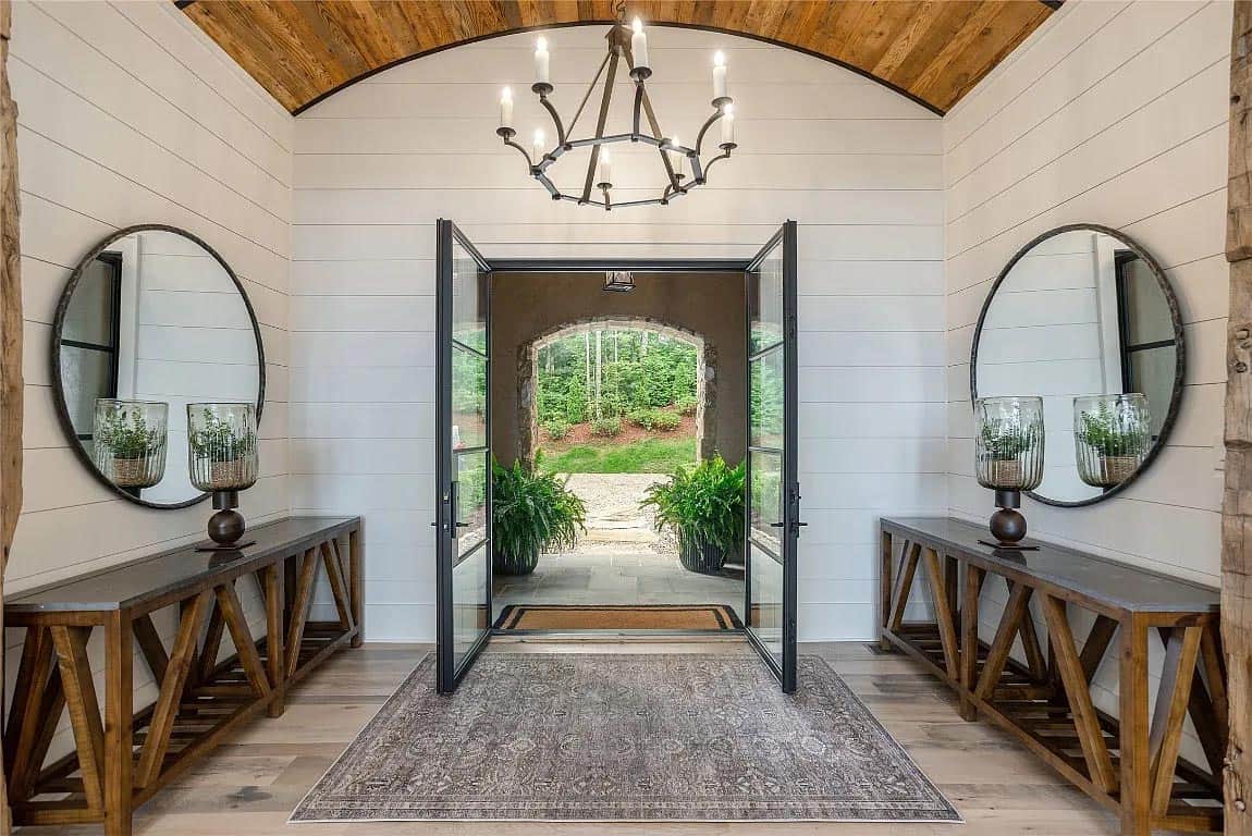 foyer, barrel vaulted wood ceiling, iron chandelier, dual round mirrors, symmetrical console tables, open front doors