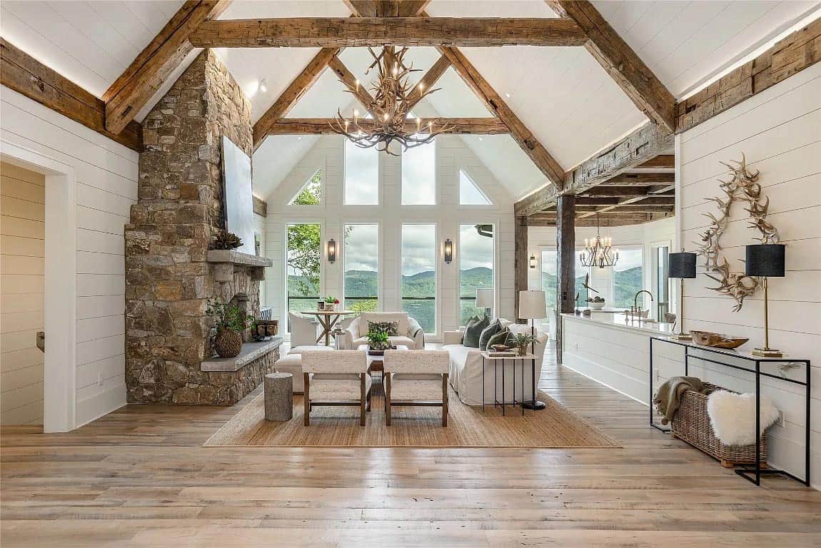 great room, stone fireplace, reclaimed wood trusses, antler chandelier, white sofas, panoramic mountain views
