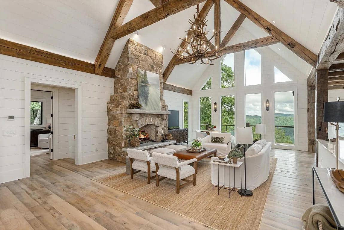 living room, stone fireplace with roaring fire, antler chandelier, reclaimed wood trusses, mountain view windows