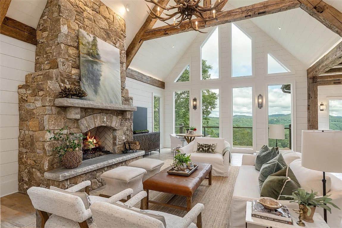 living room detail, floor-to-ceiling stone fireplace, antler chandelier, reclaimed trusses, panoramic windows