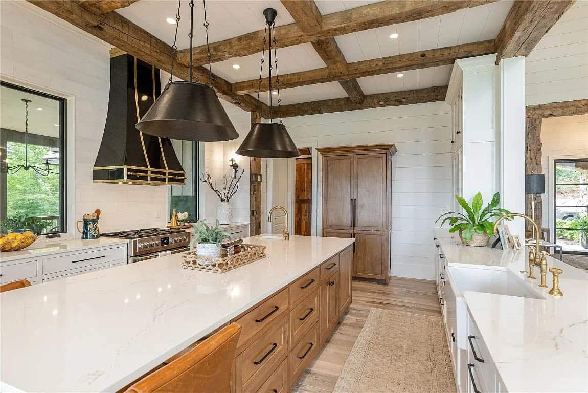 Kitchen with coffered reclaimed beam ceiling, dual black pendant lights, wood island, brass fixtures, and farmhouse sink