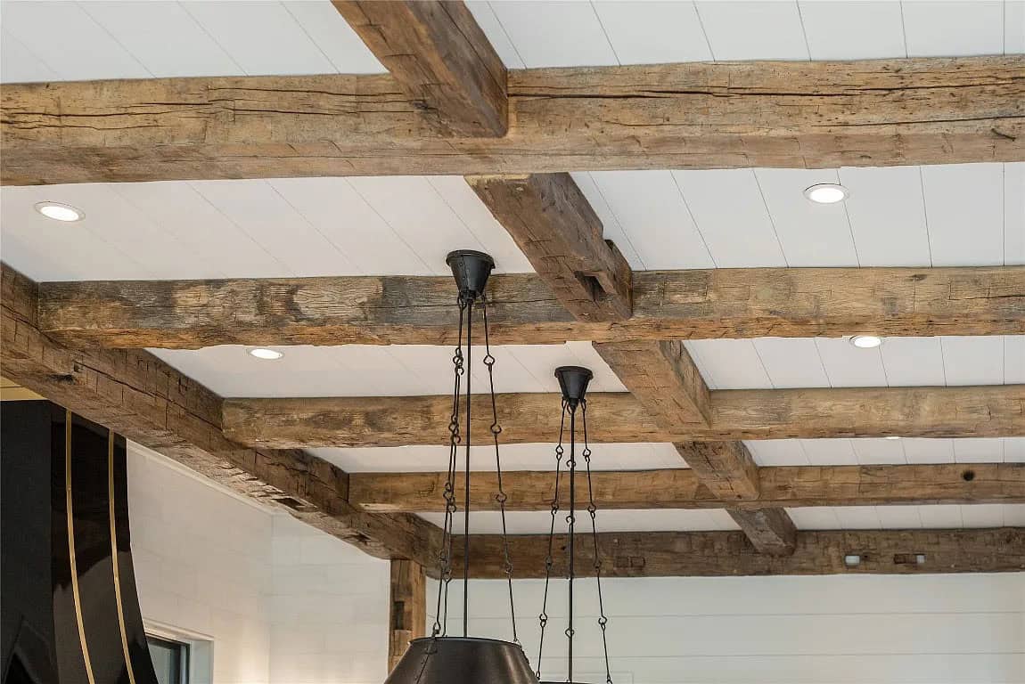 Close-up of reclaimed wood coffered beam ceiling with black iron pendant light chains in kitchen