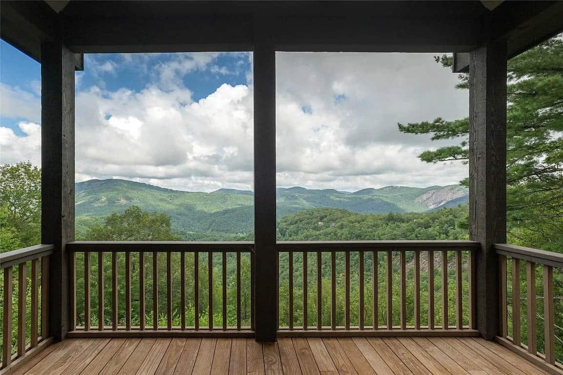 Covered deck view framed by dark timber posts looking out over forested Blue Ridge Mountain ridgeline and rocky outcropping
