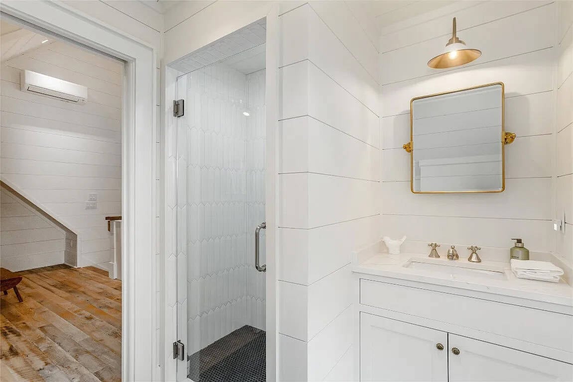 Bonus suite bathroom with a white vanity, gold-framed mirror and walk-in shower