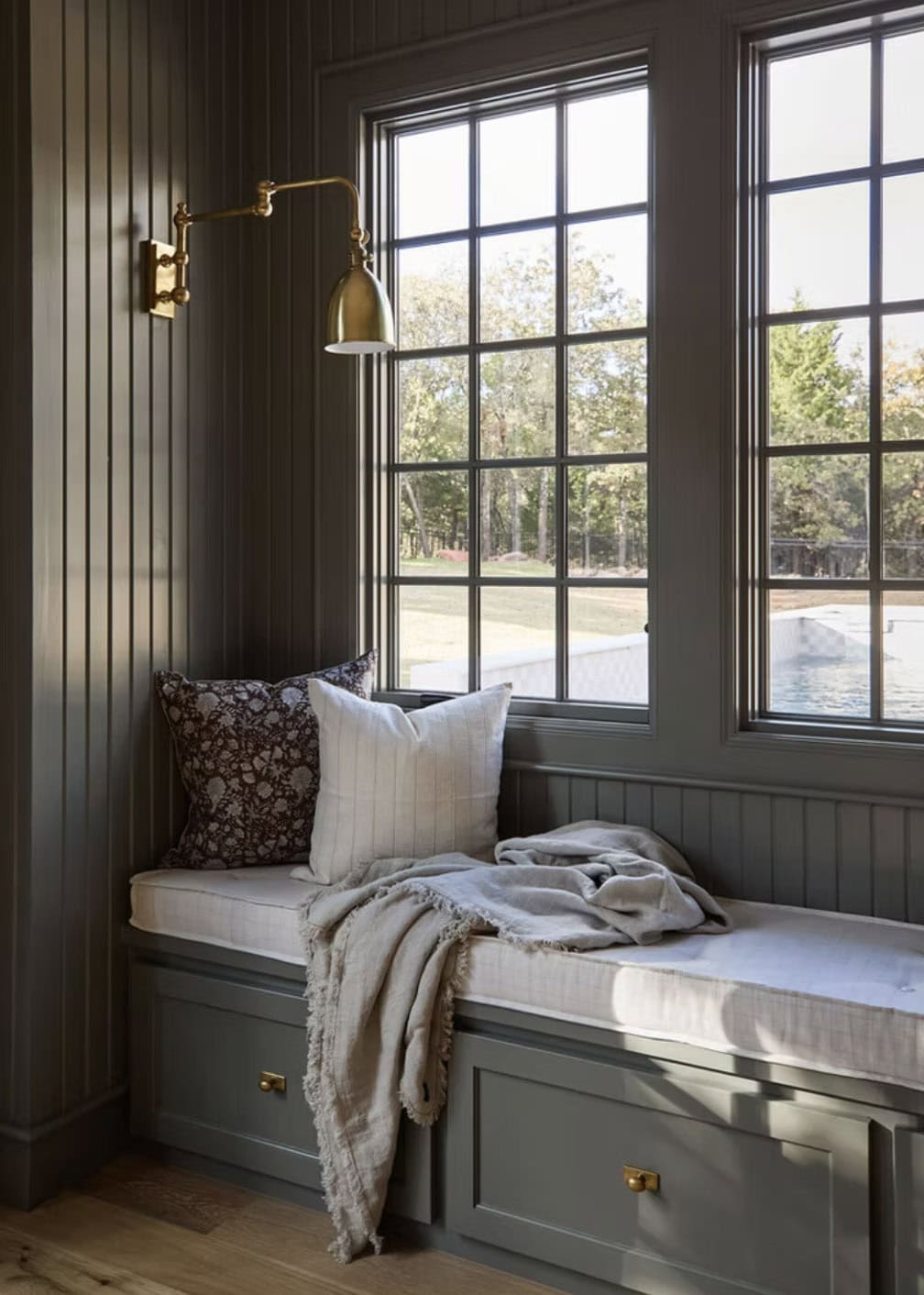 Built-In Window Seat with Brass Swing Arm Sconce and Pool View