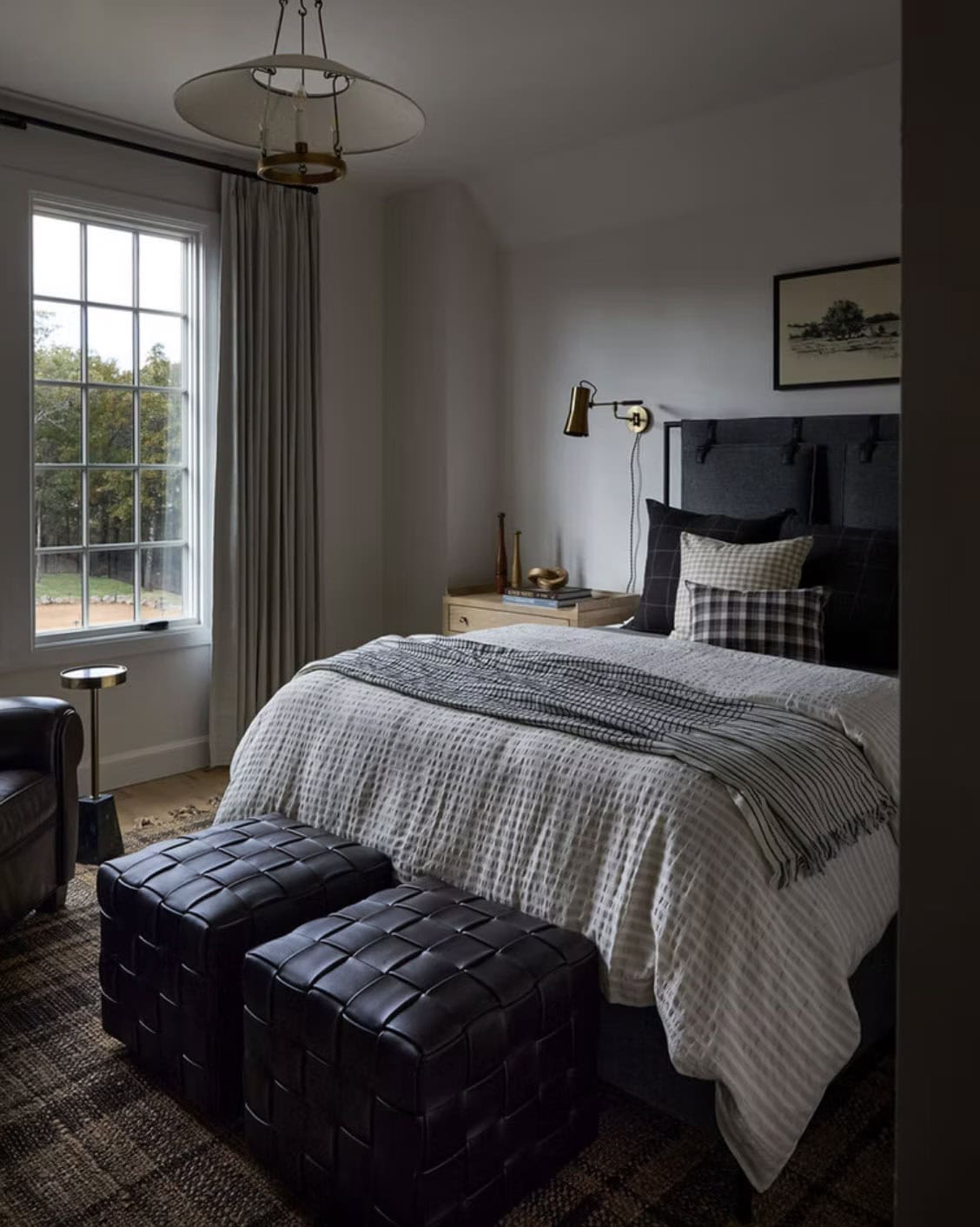 Moody Guest Bedroom with Dark Upholstered Headboard and Leather Ottomans