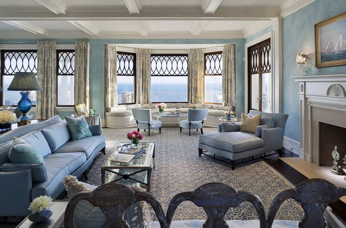 Bright coastal living room with blue decor, bay windows, ocean view, and seating area