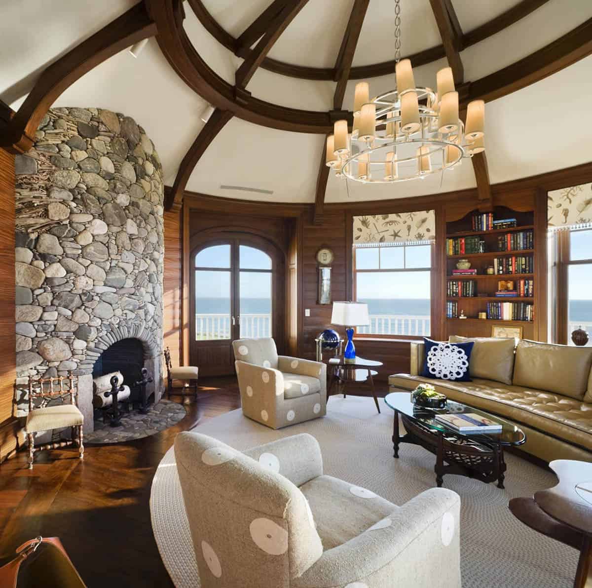 Shingle-style living room with stone fireplace, vaulted wood ceiling, and ocean views