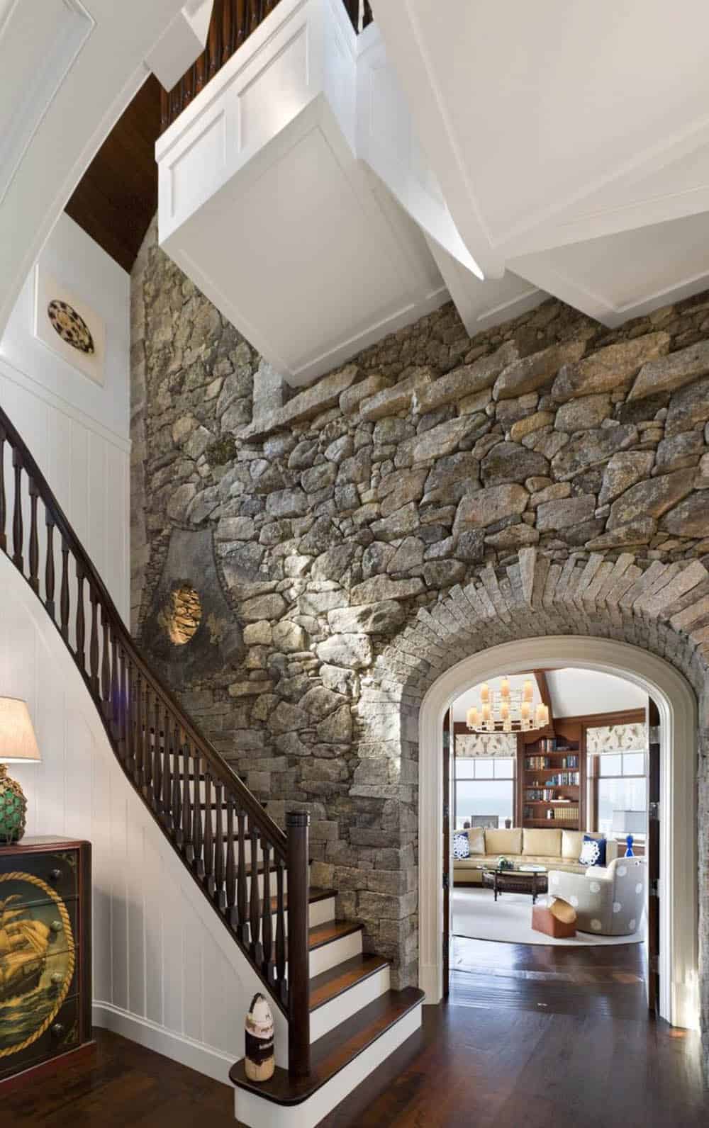 Stone accent wall with staircase and arched doorway leading to living room