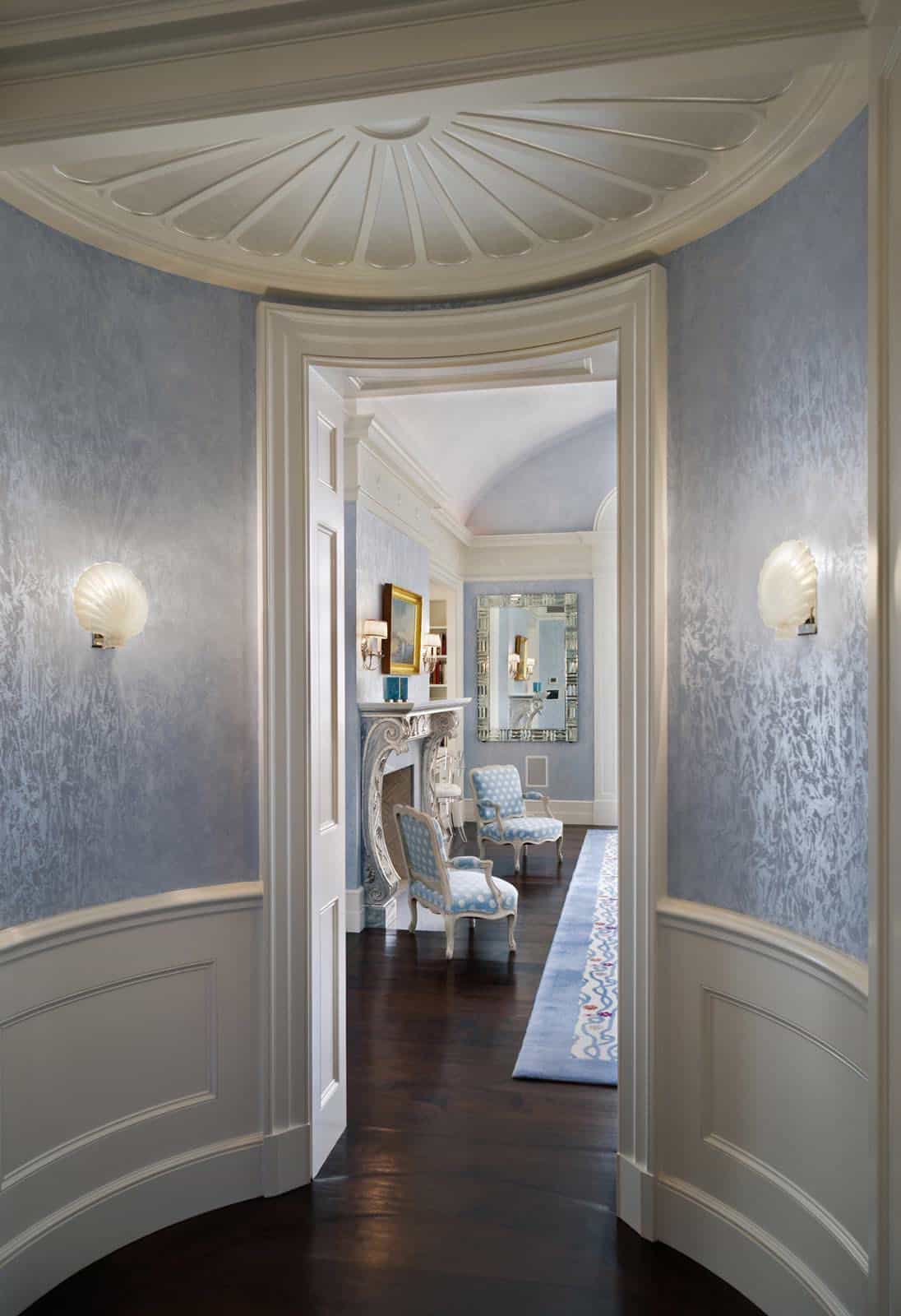 Circular vestibule with shell-motif ceiling medallion, blue textured walls, shell-shaped sconces, and double doors opening to the master bedroom