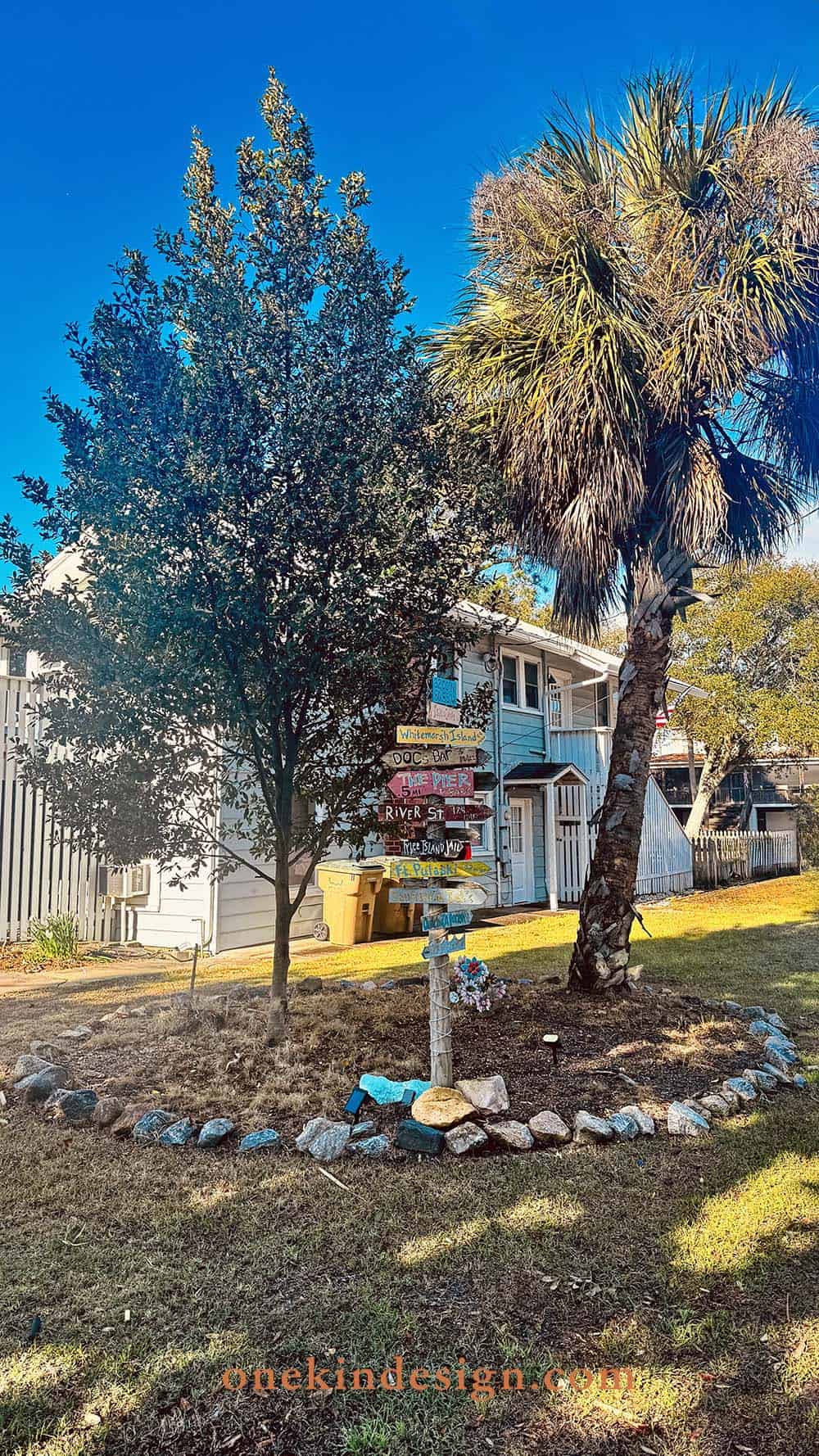Rock border surrounding a tree base with a colorful directional sign post on Tybee Island, Georgia
