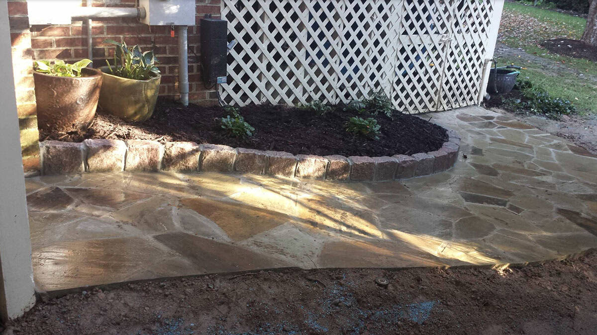 Natural flagstone walkway with curved stone curbing defining a mulched planting bed