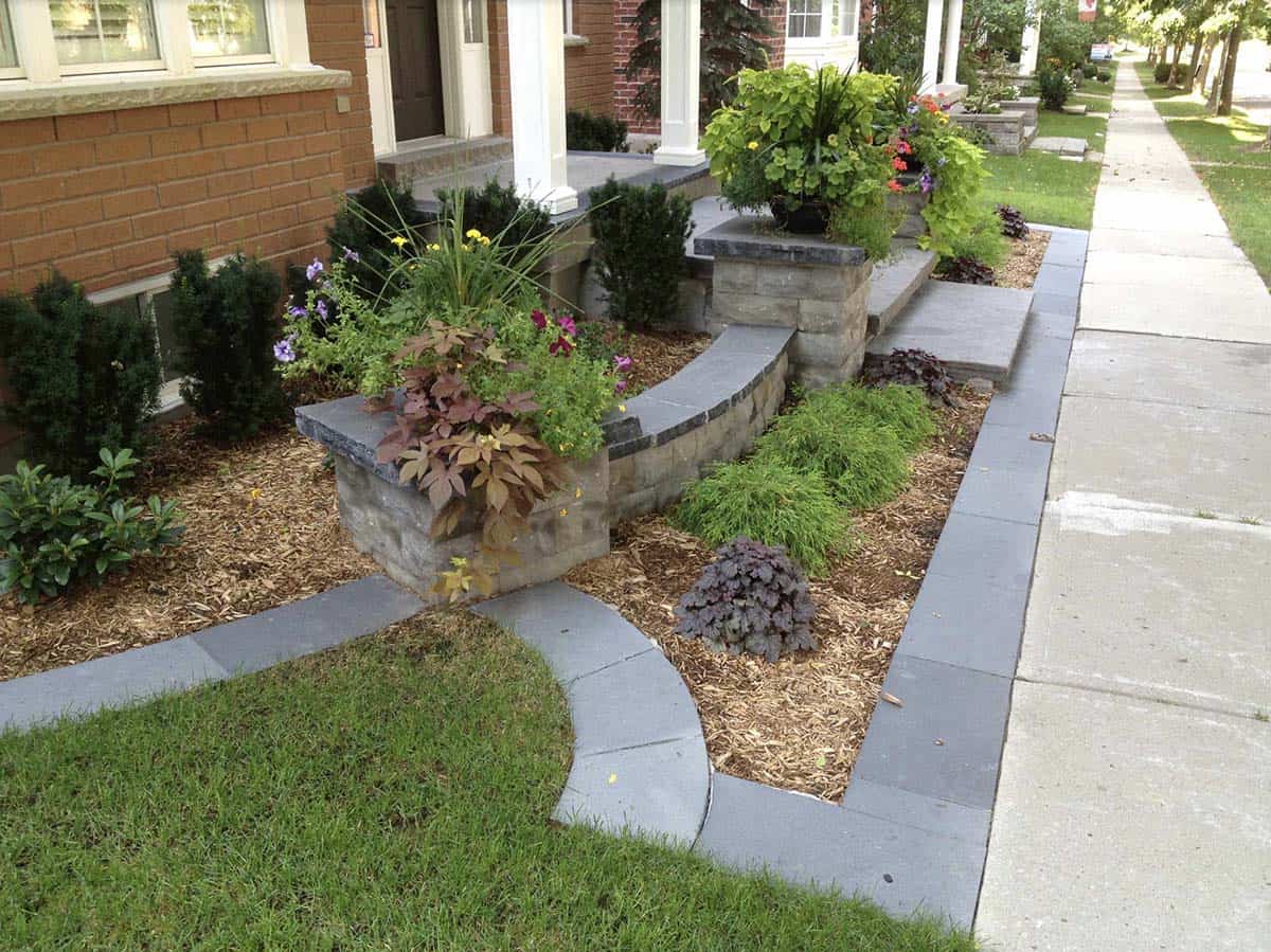 Custom cut natural stone steps and slate grey walkway with raised stone planter walls on a urban front yard