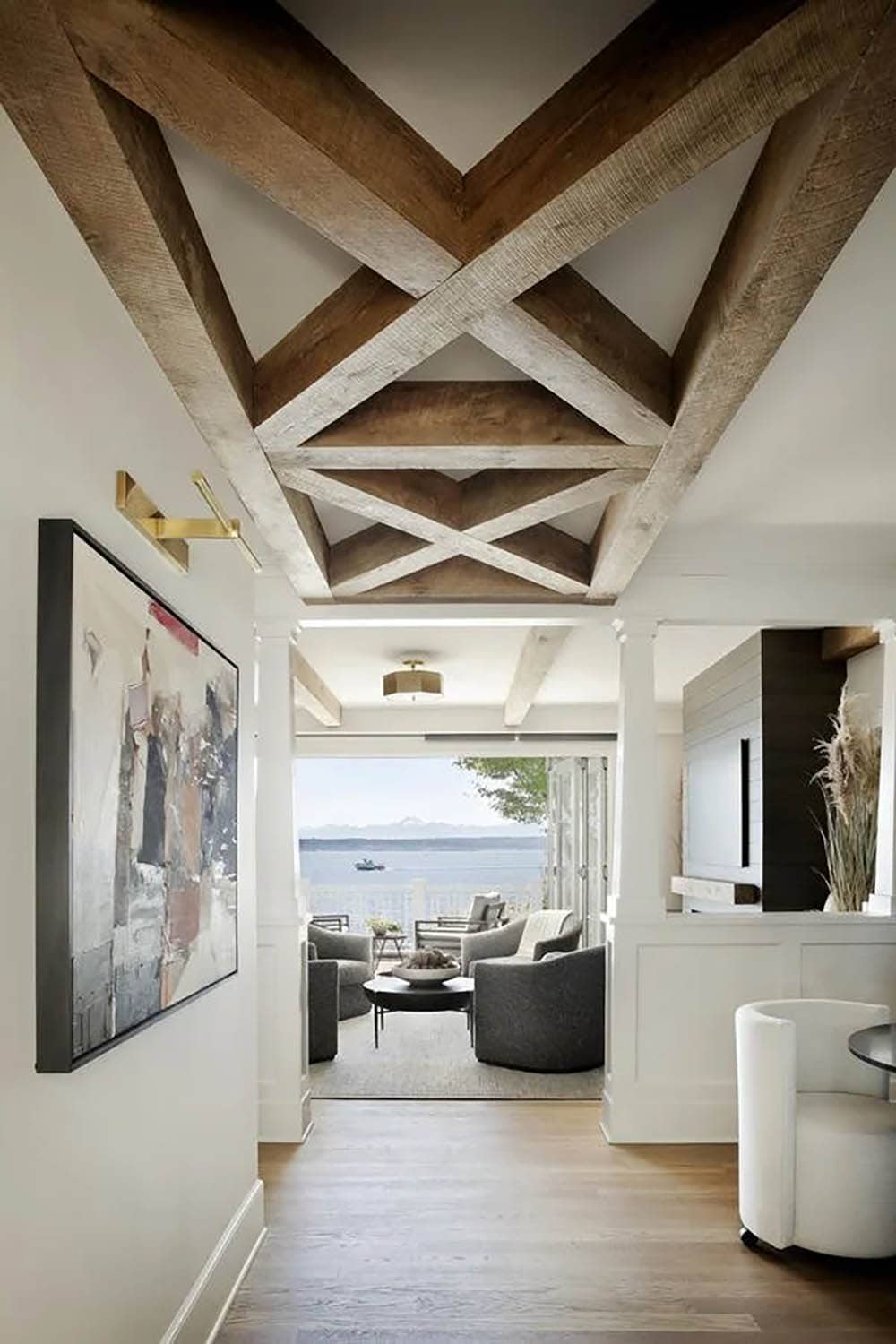 Entry hallway with dramatic crossed wood beam ceiling leading to water-view living room