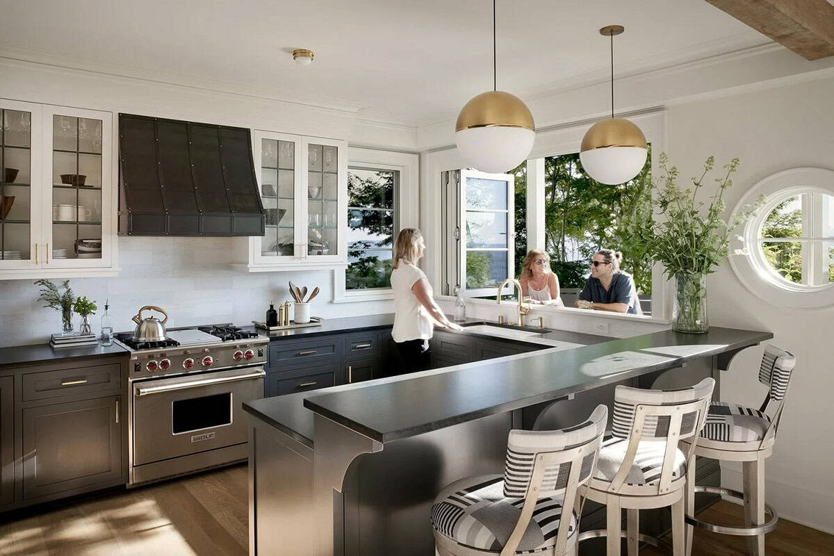 Kitchen with Wolf range, dark countertops, pass-through window, and gold globe pendants