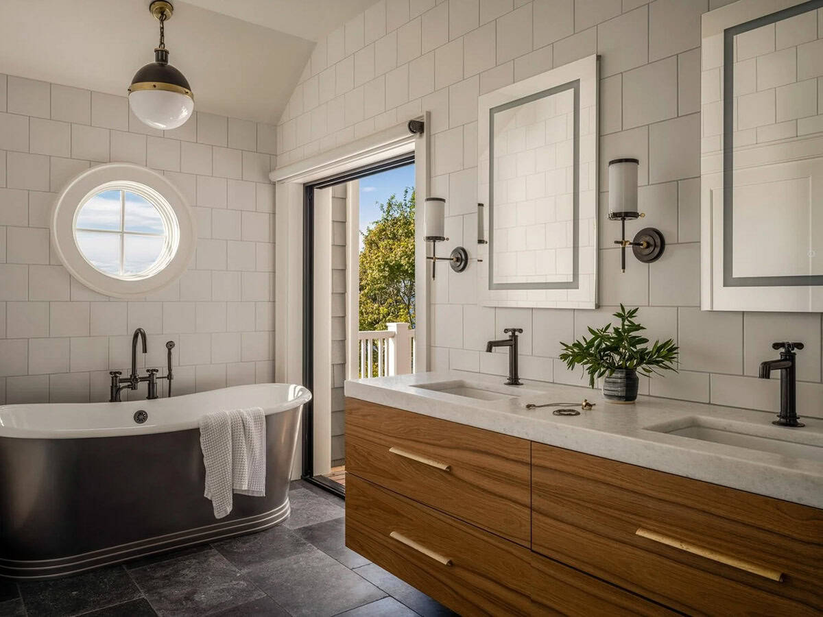 Primary bathroom with dark soaking tub, walnut floating vanity, matte black fixtures, and porthole window