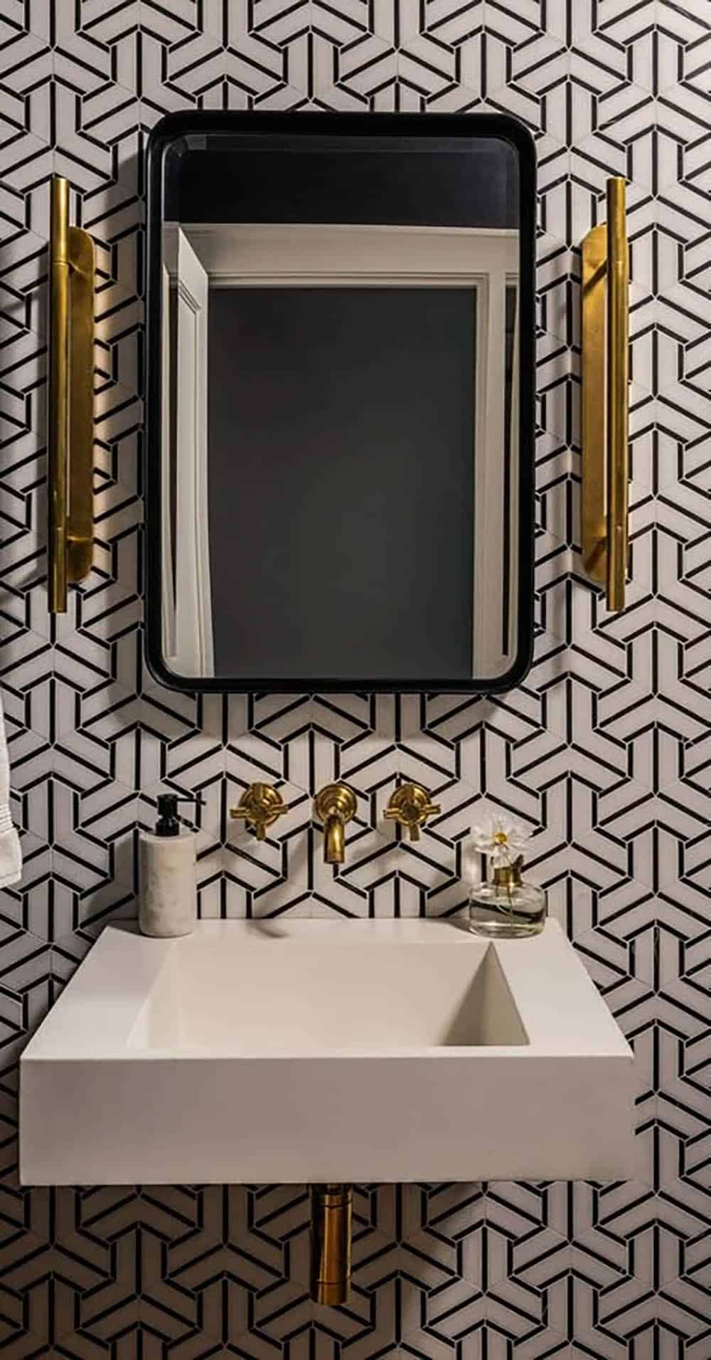 Powder room with bold black-and-white geometric tile, floating white sink, black mirror, and brass wall sconces