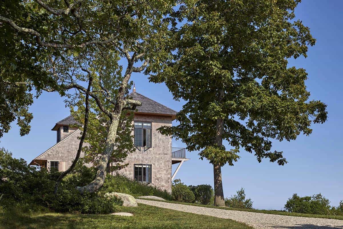 Three-story cedar shingle tower house framed by mature oak trees with small balcony