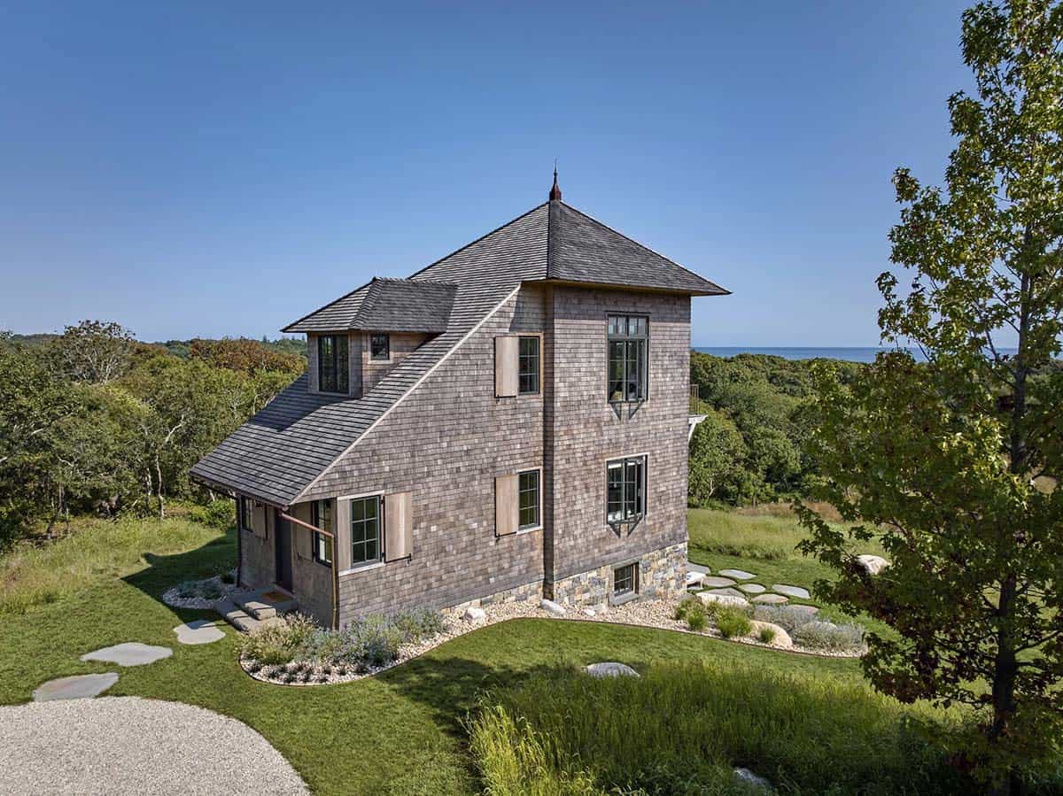 Aerial view of cedar shingle and stone tower house with slate roof and copper finial