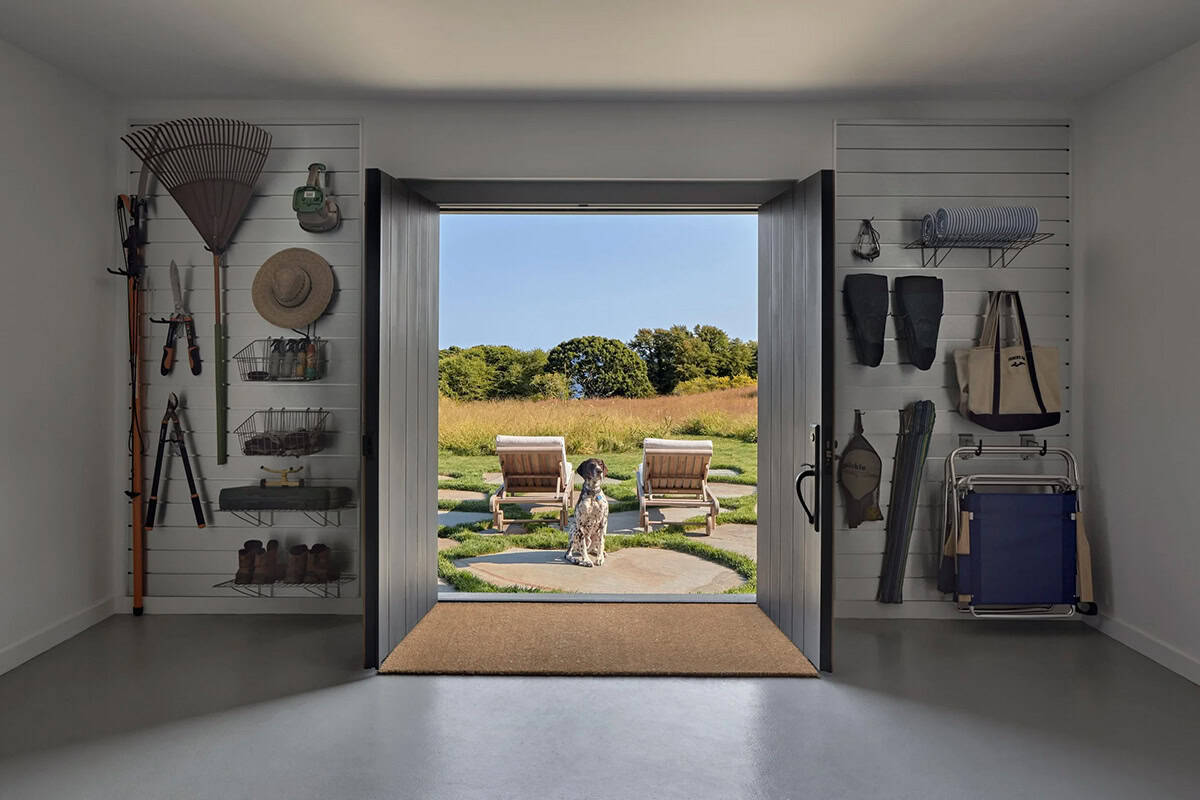 Organized mudroom with garden tools and beach gear flanking open double doors with dog outside