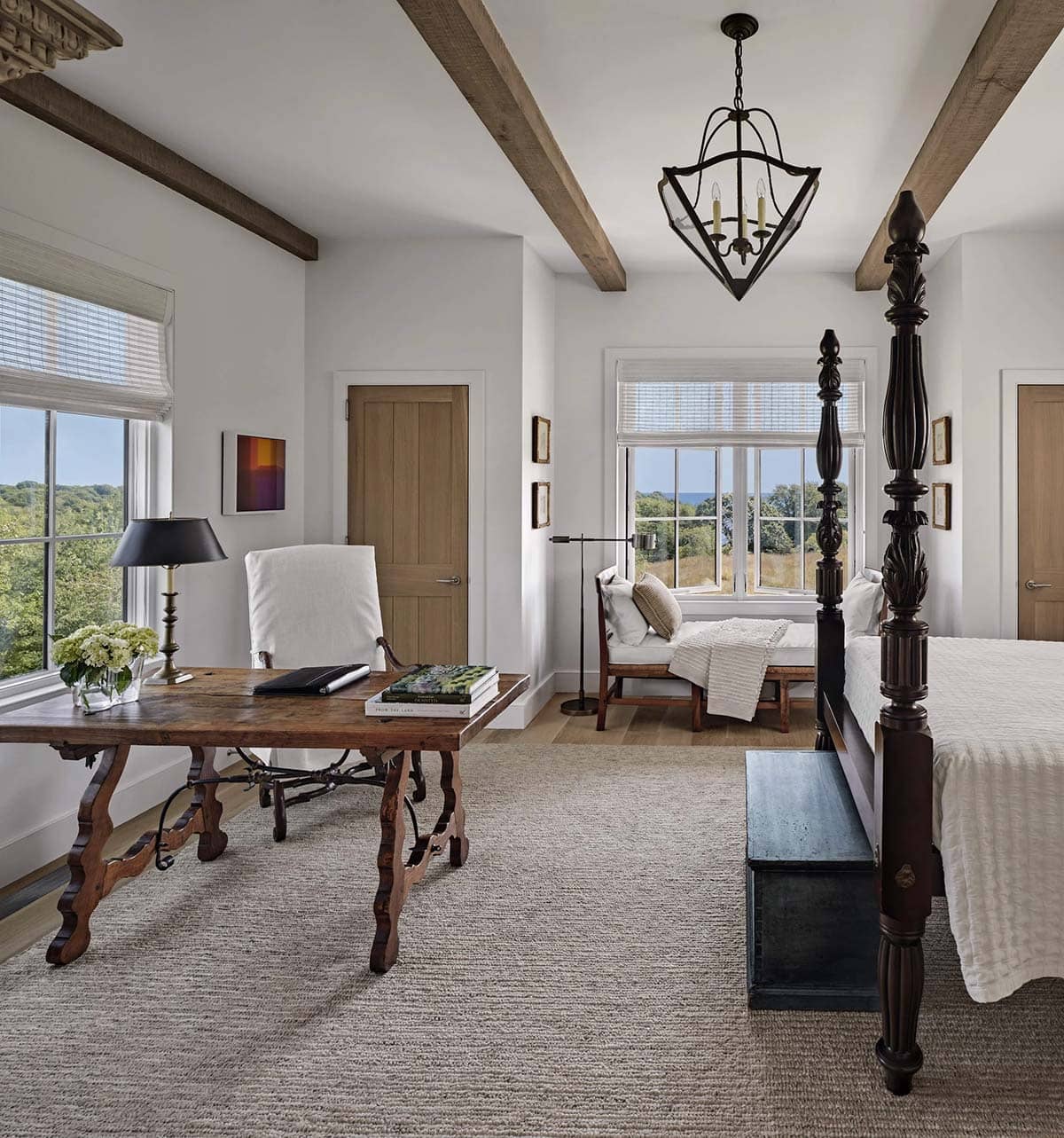 Primary bedroom with four-poster bed, antique writing desk, window seat, and ocean views