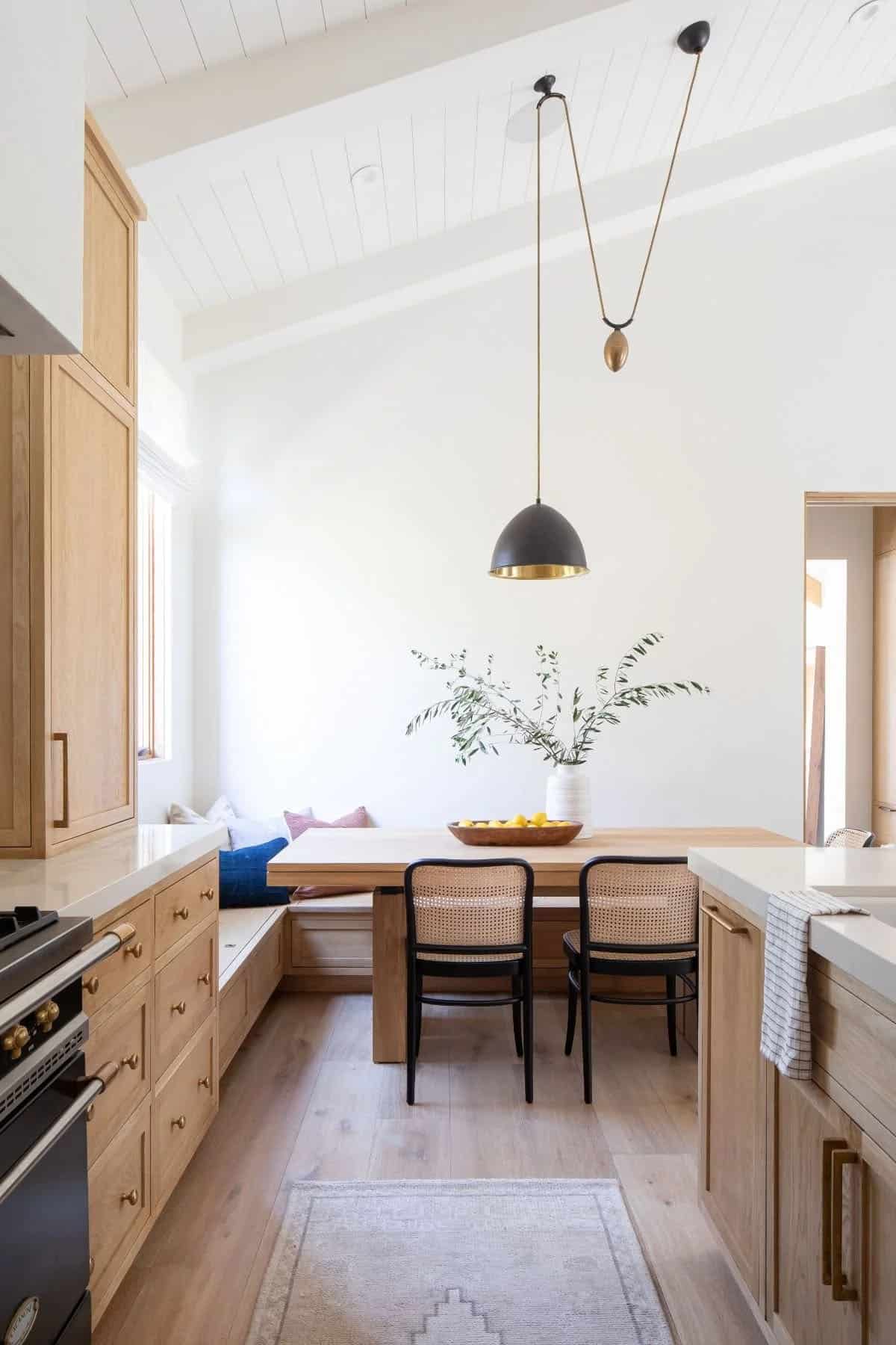 Kitchen breakfast nook with built-in oak banquette, cane dining chairs, wood table, and black dome pendant light