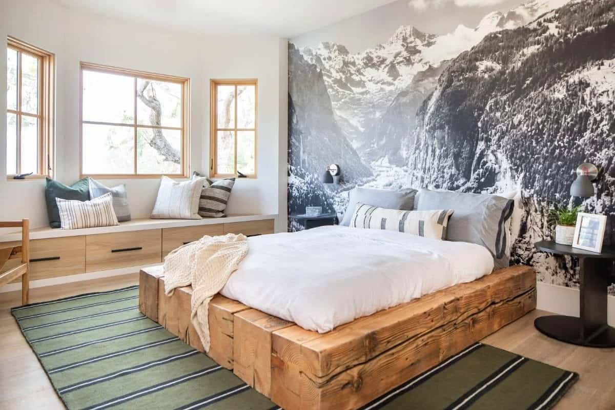Boy's bedroom with rustic wood beam platform bed, black-and-white mountain mural wallpaper, and striped rug