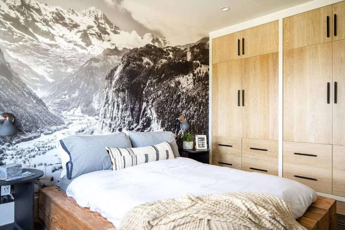 Boy's bedroom with mountain mural wallpaper, rustic wood platform bed, and floor-to-ceiling oak wardrobe