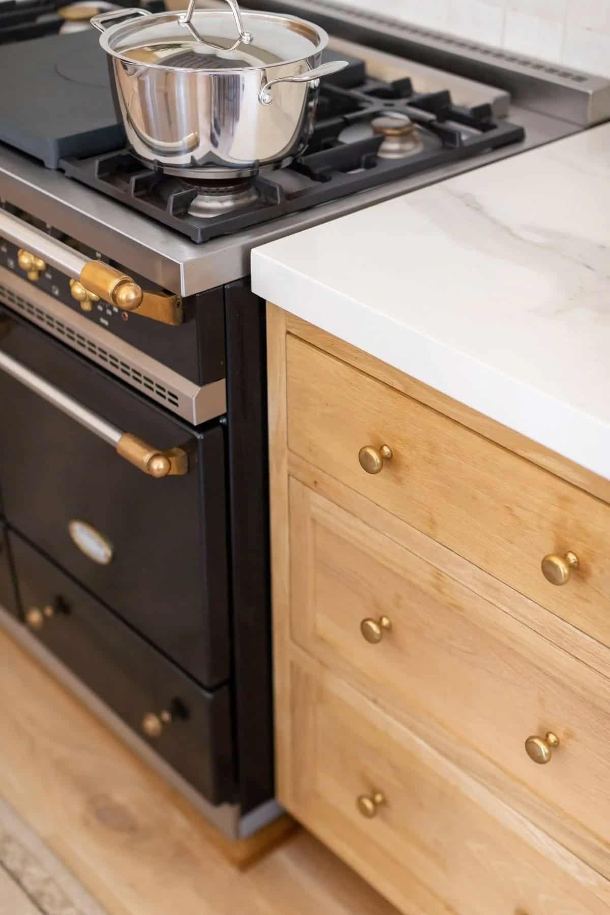 kitchen detail, black and brass range, white oak drawers, marble countertop, brass knobs