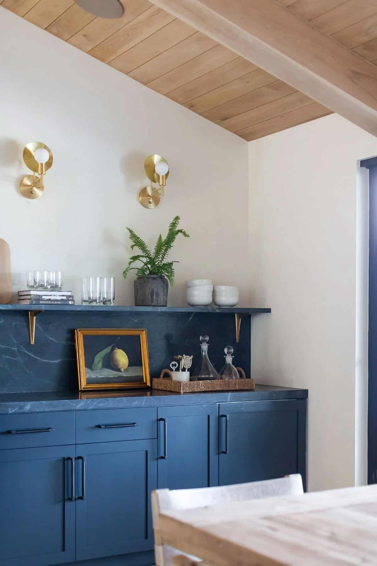 dining room sideboard, navy blue cabinetry, green marble backsplash, brass sconces, wood plank ceiling