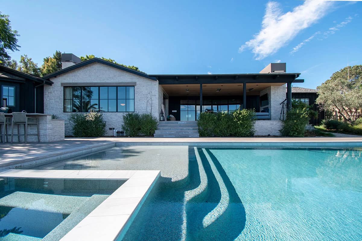 Modern infinity pool and hot tub with a view of the home exterior