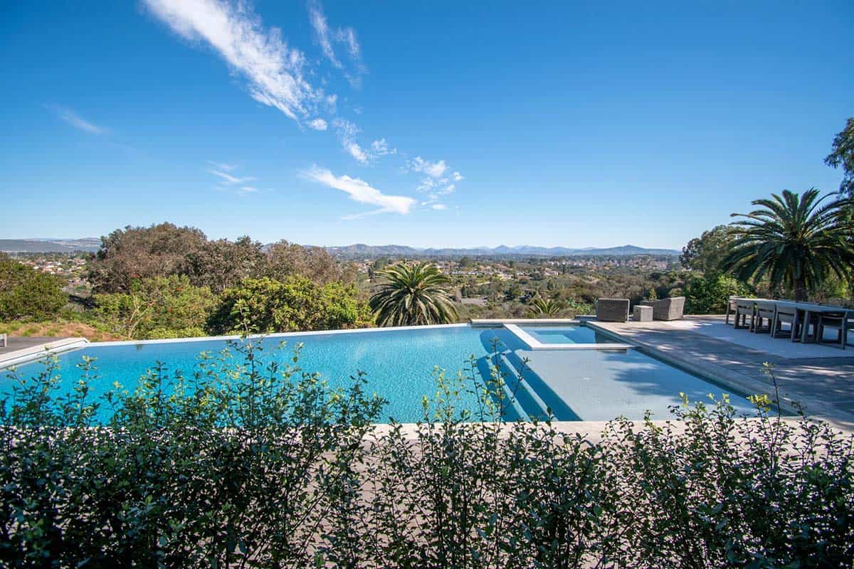 Modern infinity pool and hot tub on a patio overlooking a valley