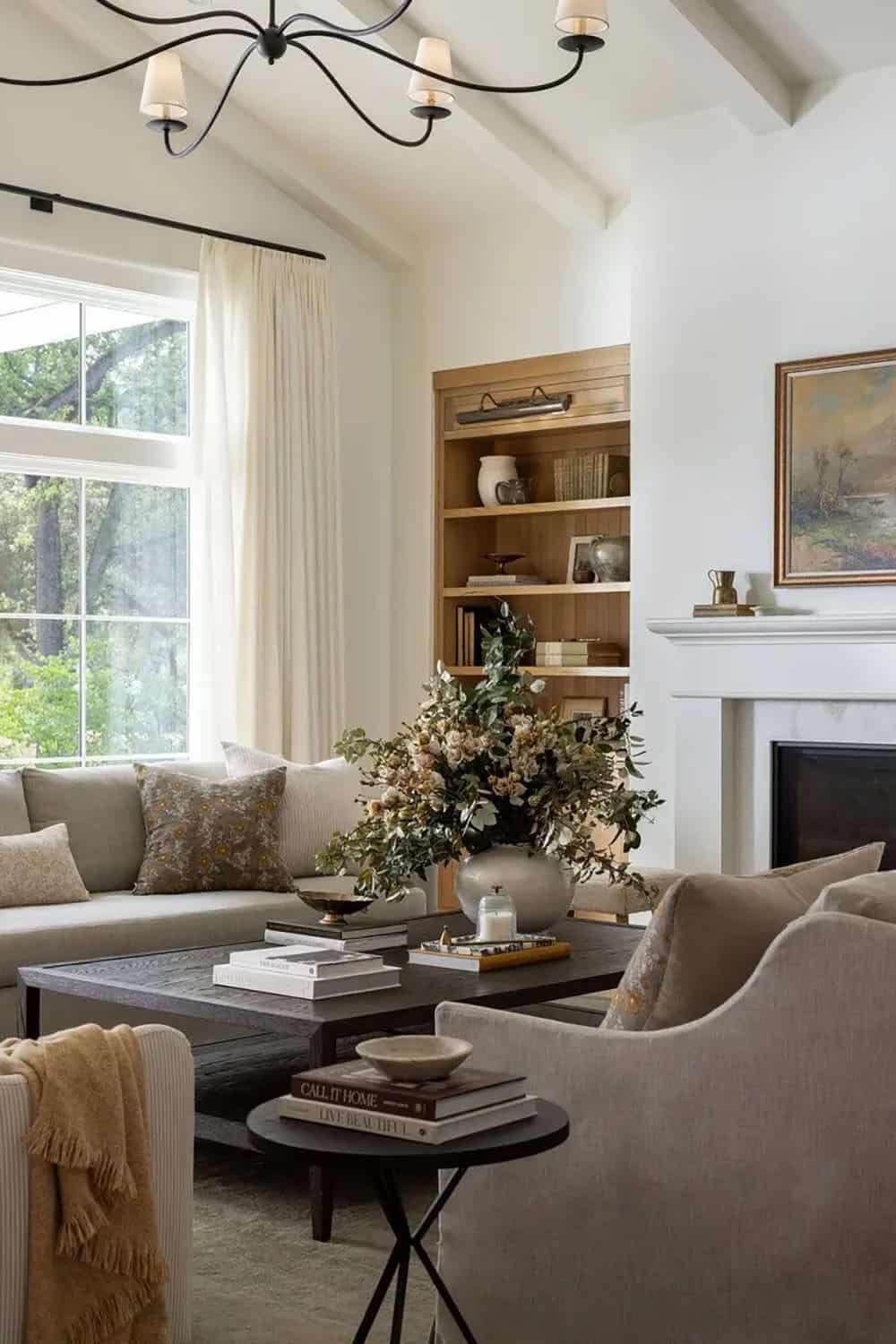 Living room with vaulted beamed ceiling, linen sofa, dark wood coffee table, and large floral arrangement